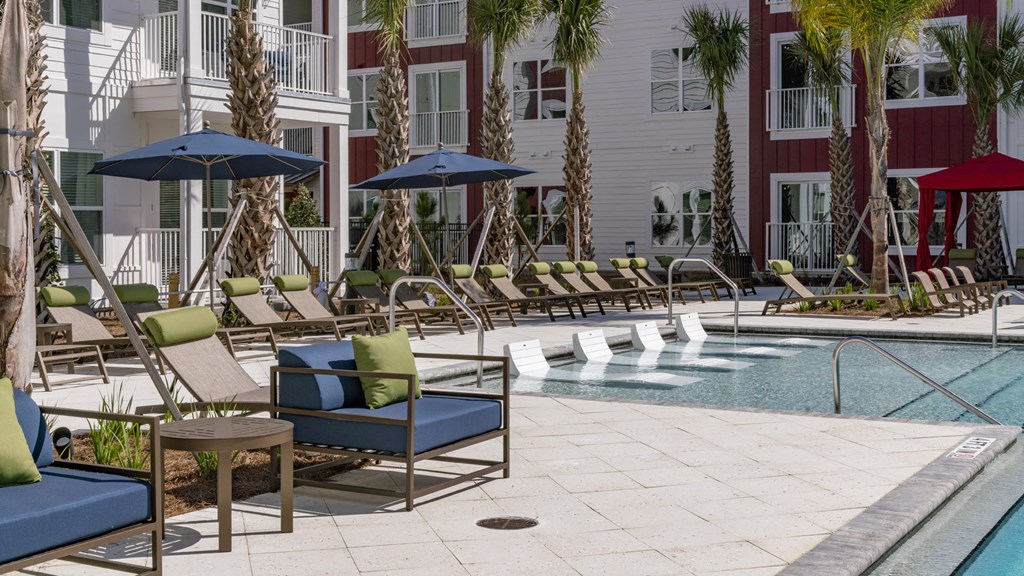 a swimming pool with lounge chairs and umbrellas in front of a building
