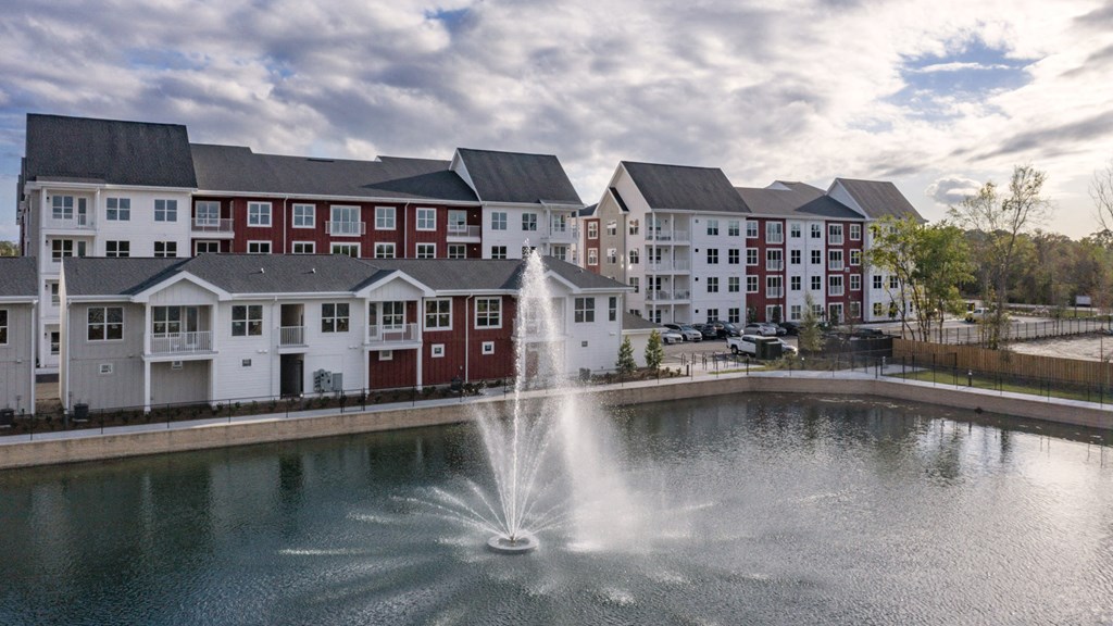 a fountain in the middle of a pond in front of an apartment building