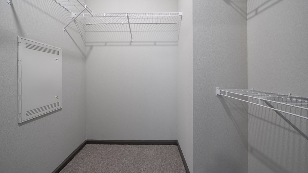 the walk in closet in a small room with a white door and a white wardrobe