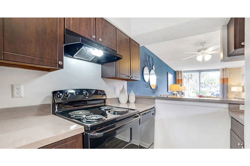 Dark wood kitchen cabinetry with a black refrigerator and tile backsplash at Midora at Woodmont in Tamarac, FL