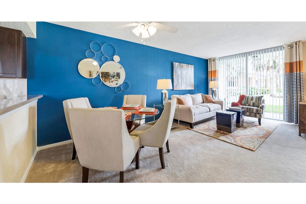 Living room and dining room area with plush carpeting and ample natural light in your home at Midora at Woodmont in Tamarac, FL