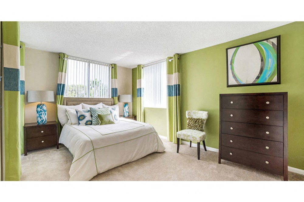 Spacious bedroom with plush carpeting and large window at Midora at Woodmont in Tamarac, FL