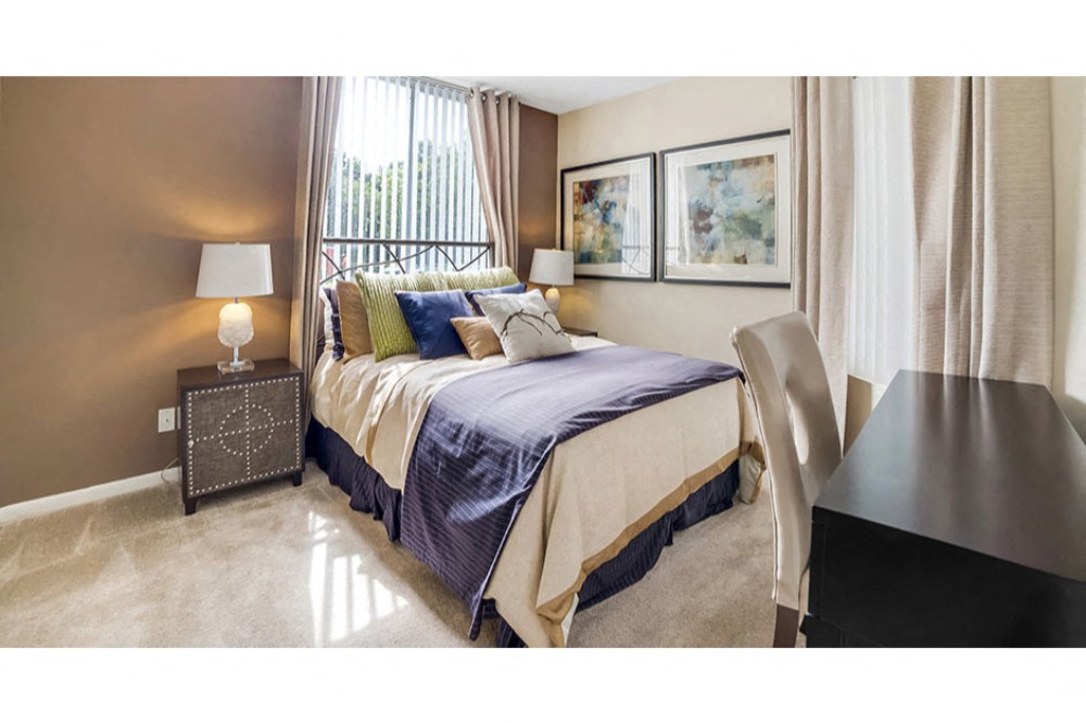 Spacious bedroom with plush carpeting and large window at Midora at Woodmont in Tamarac, FL