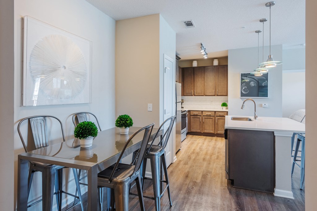 a dining area with a table and chairs and a kitchen in the background