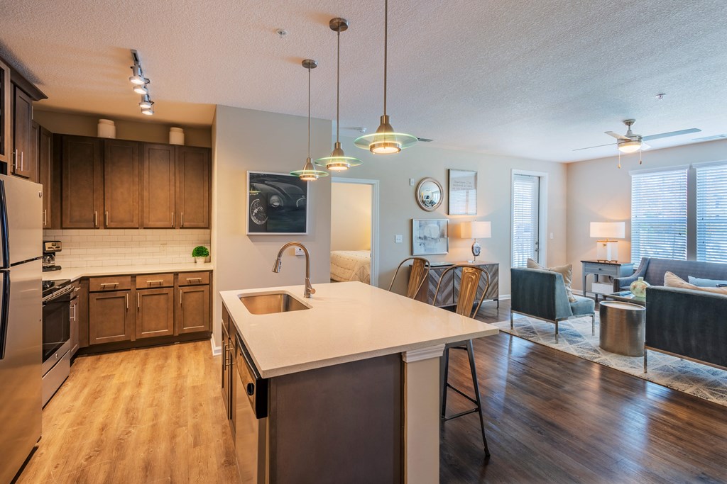 a kitchen with a large center island next to a living room with a couch and a chair