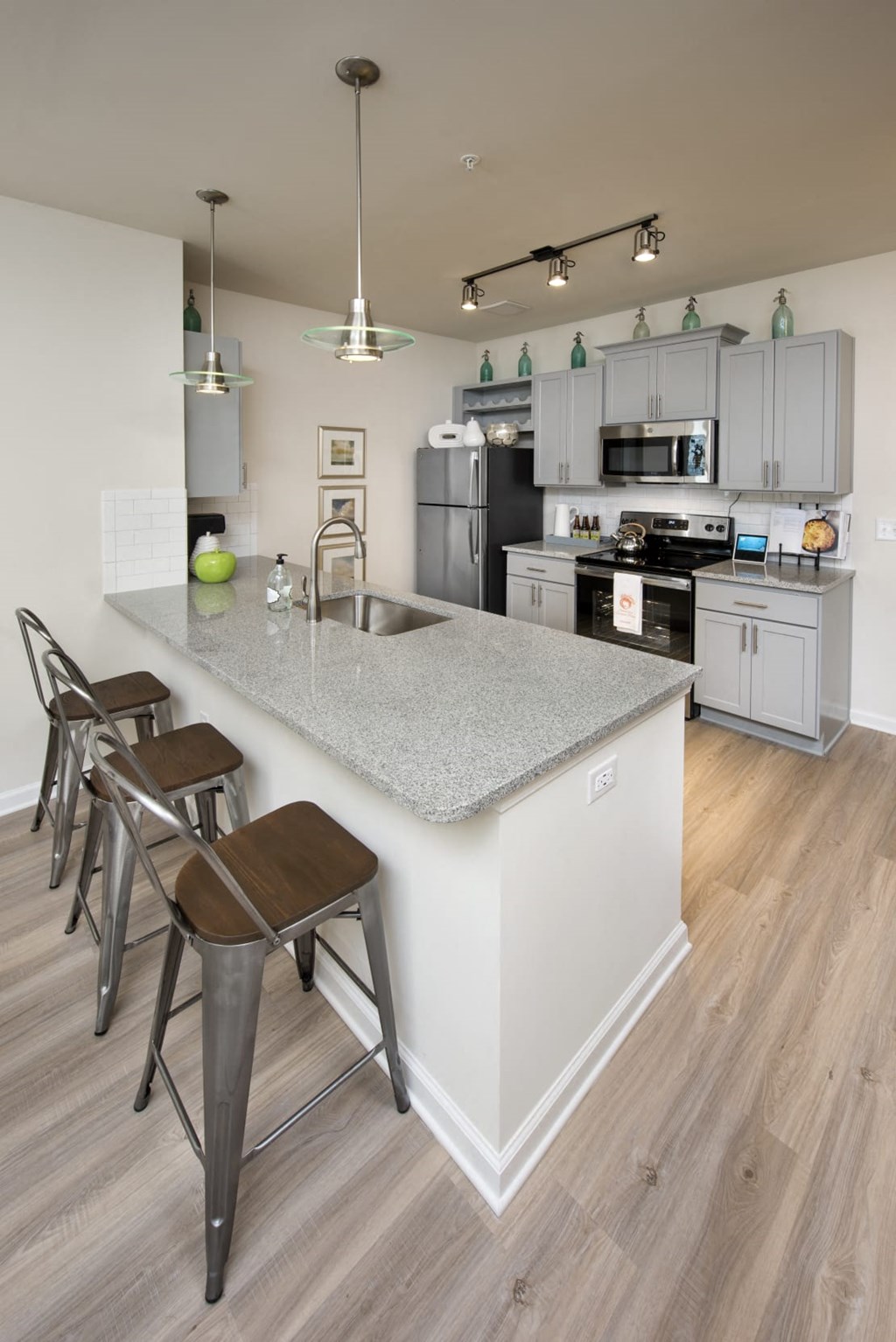 a kitchen with a large island with a sink and three stools in front of it
