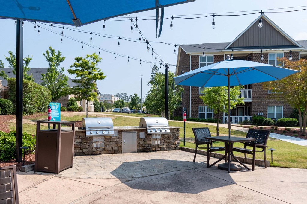 our patio has a grill and table with umbrellas