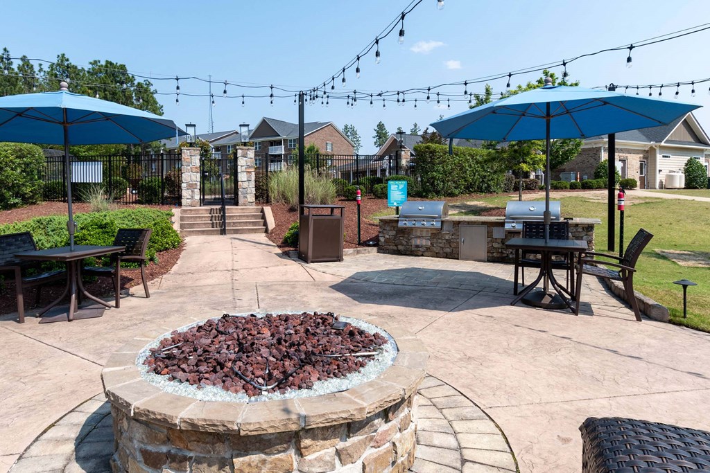 a patio with umbrellas and tables and a fire pit