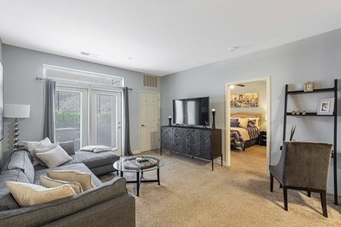 A living room with a grey couch and a glass coffee table.