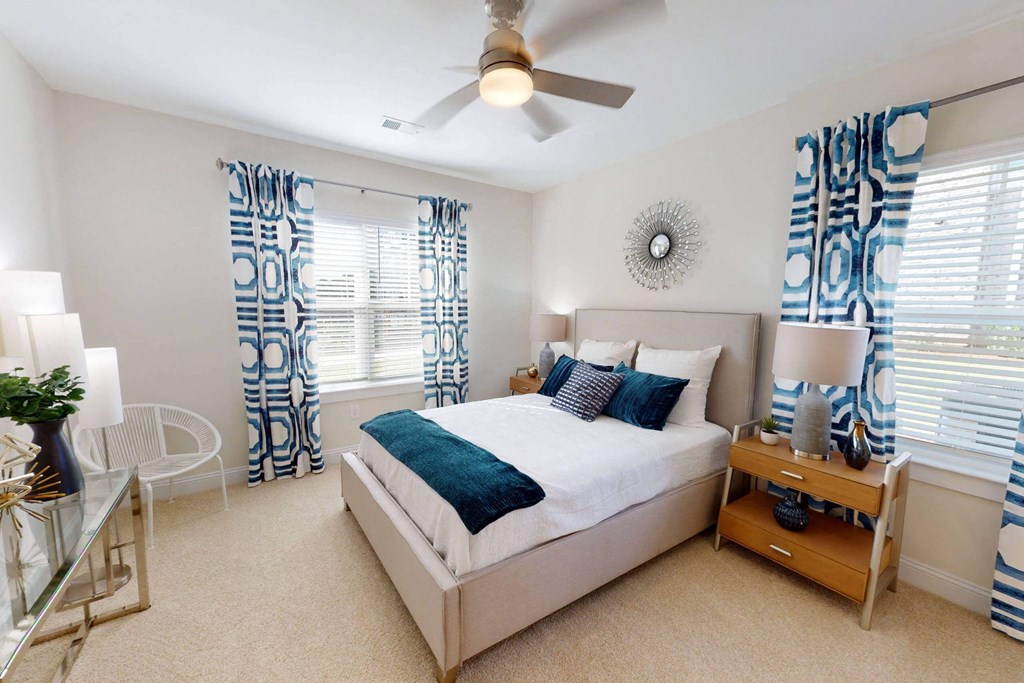 a bedroom with a bed and windows with curtains