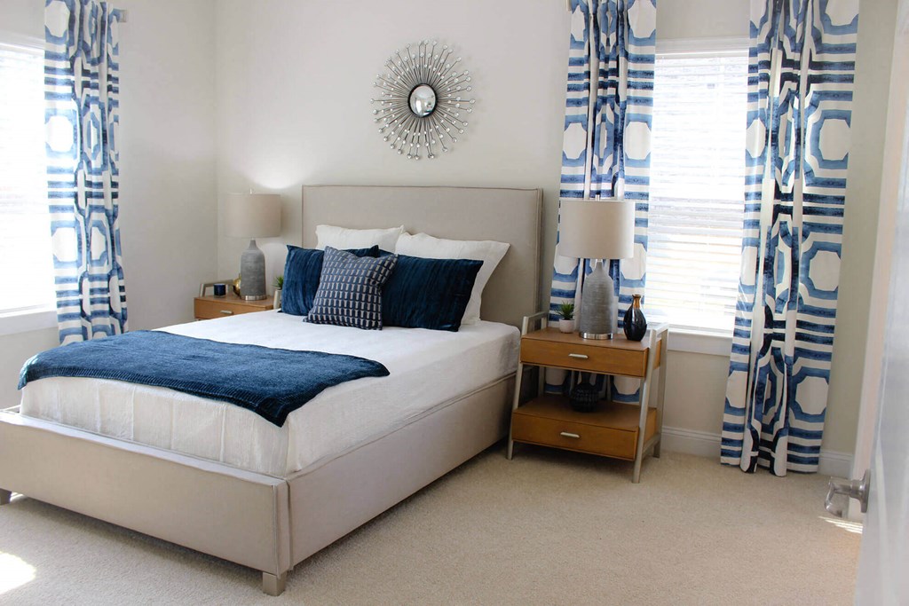 a bedroom with blue and white curtains and a bed