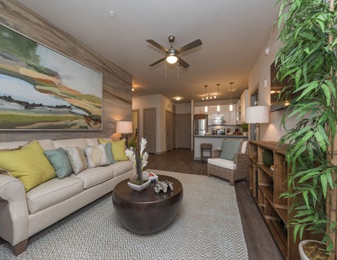 A living room with a large painting on the wall and a couch with yellow pillows.