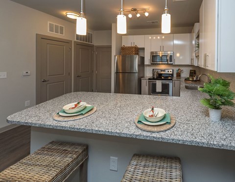 A kitchen with granite countertops and a stainless steel refrigerator.