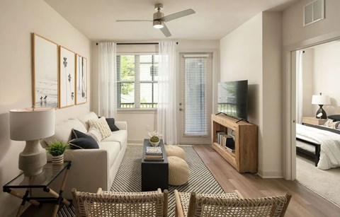 A living room with a white couch, a glass coffee table, and a television.