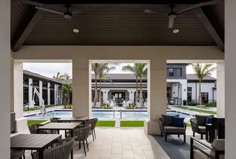 A patio with a table and chairs overlooking a pool.