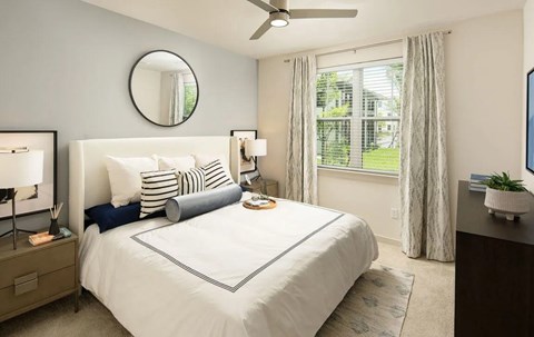 A well-lit bedroom with a large bed and a ceiling fan.