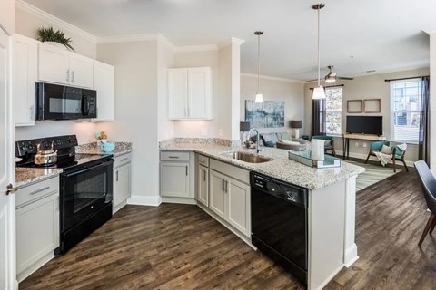 A kitchen with black appliances and white cabinets.