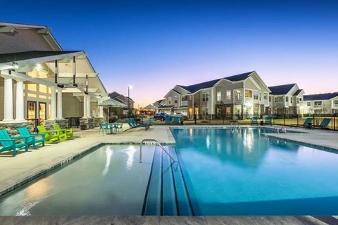 A swimming pool in front of a building with a sunset in the background.