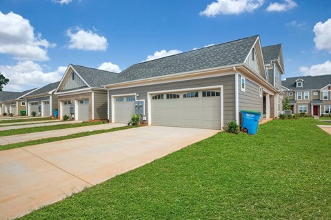 A row of houses with a blue trash bin in front of the garage.