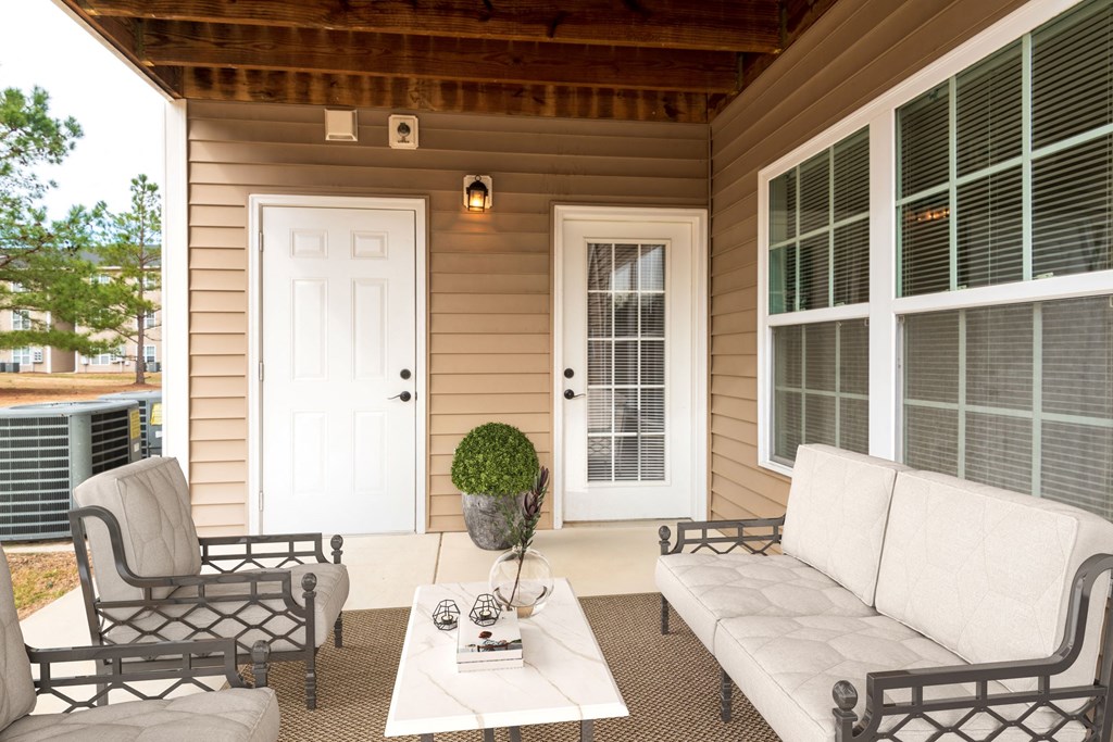 a porch with a white couch and chairs and a table