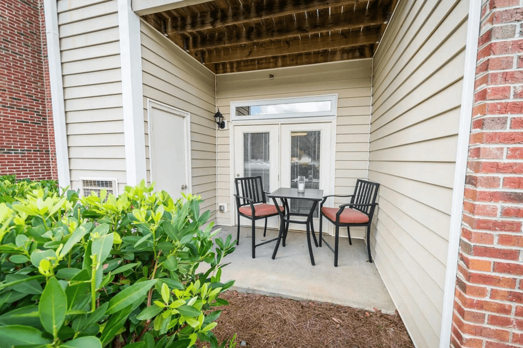 a patio with a table and chairs in front of a house