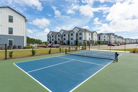 A tennis court is surrounded by apartment buildings at Evolve Holly Ridge Apartments in Holly Ridge, NC.