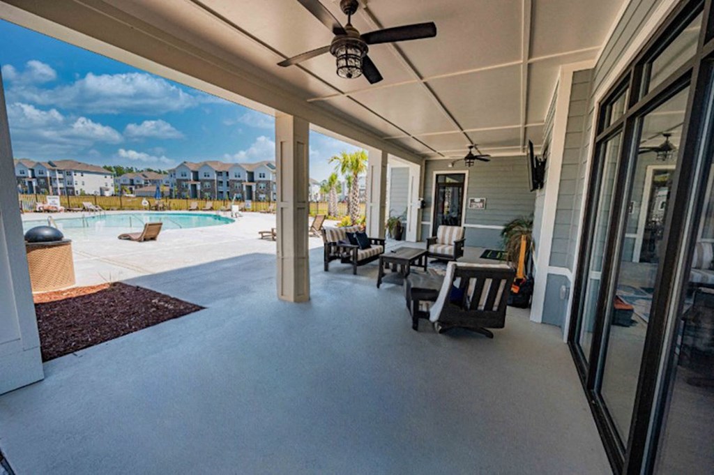 a covered porch with a pool and chairs and a ceiling fan