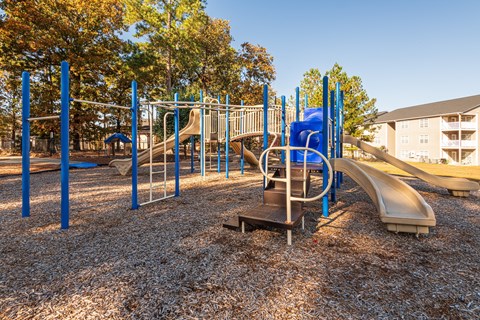 A playground with a slide, swings, and monkey bars.