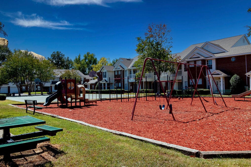 a playground with a swing set in front of houses