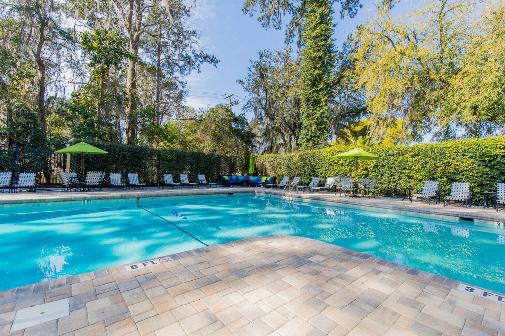a swimming pool with chairs and umbrellas next to a resort style pool