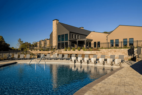 A pool with chairs and a building in the background at Terraces at High Mountain apartments in Huntsville, AL.