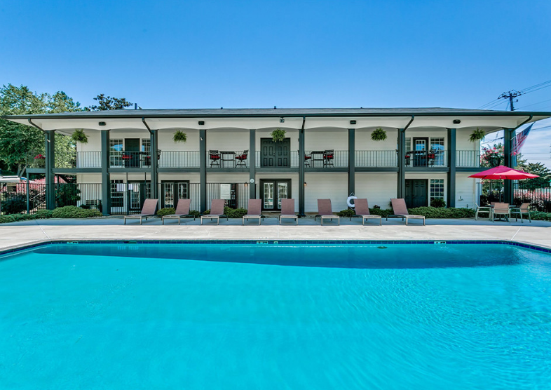 a large pool in front of a hotel with chairs and a umbrella