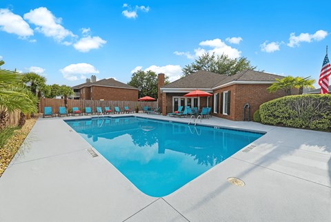A swimming pool in a backyard with a house and trees in the background.