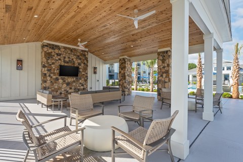 A patio with a stone fireplace and chairs. at Evolve Holly Ridge Apartments in Holly Ridge, NC
