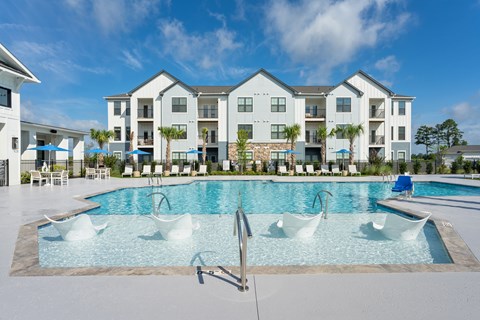 A large swimming pool in front of apartment buildings at Evolve Holly Ridge Apartments in Holly Ridge, NC.