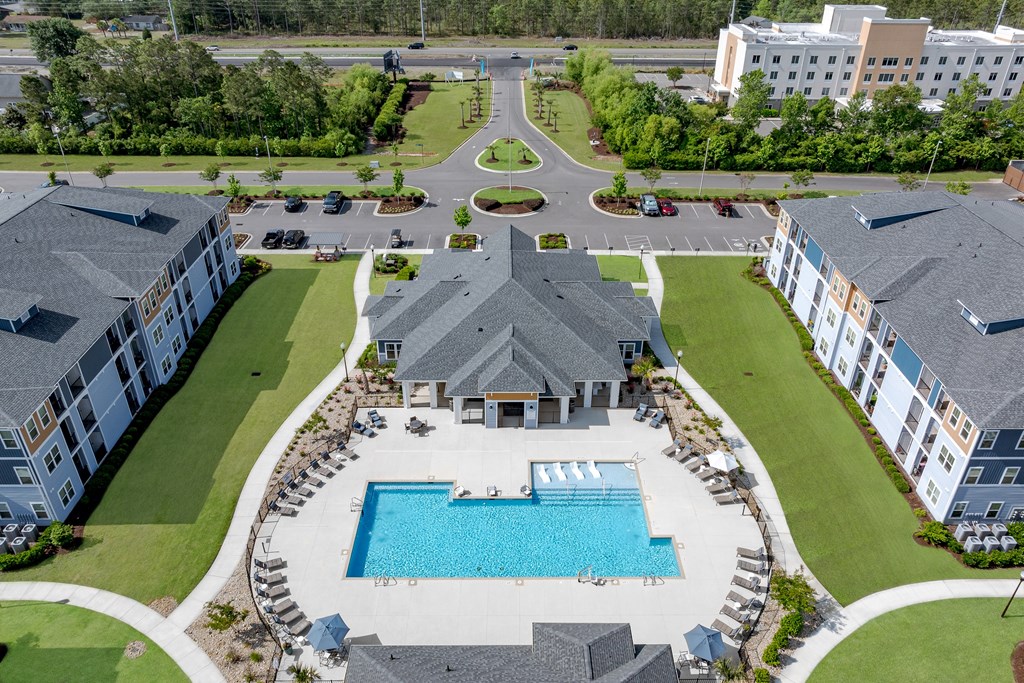 A large swimming pool surrounded by a grassy area and a building in the background.