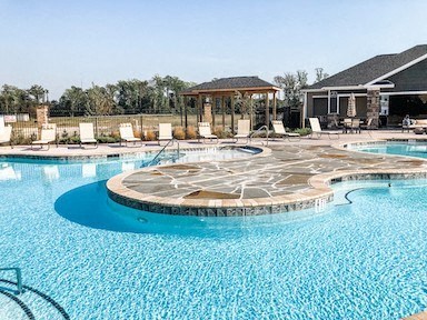 a large swimming pool with chairs and a spa