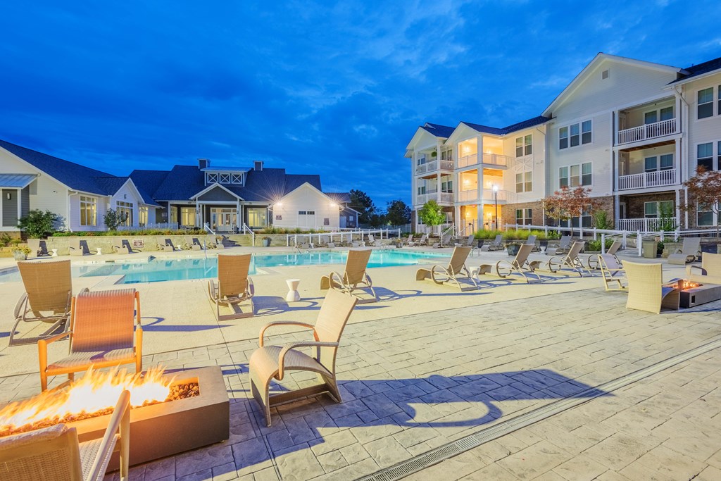 a swimming pool with chaise lounge chairs and fire pits at the enclave at woodbridge apartments