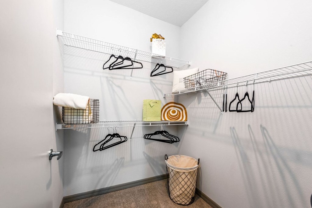 a walk in closet with shoe racks and a trash can