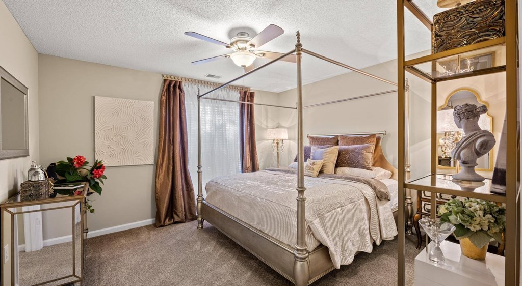 A bedroom with a four poster bed and a ceiling fan at Palmetto Pointe apartments in Myrtle Beach, SC.