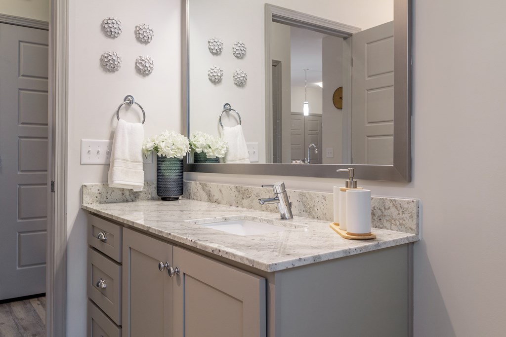 A bathroom with a marble countertop and a large mirror.