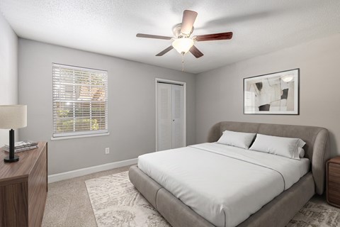 A bedroom with a bed, a ceiling fan, and a window with blinds.