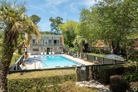 A house with a pool surrounded by greenery.