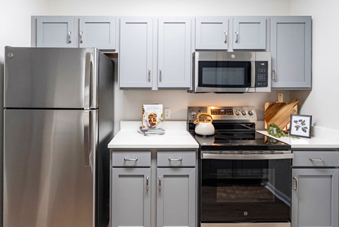 A modern kitchen with a stainless steel refrigerator and a black stove top.