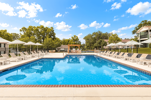 A large swimming pool surrounded by lounge chairs and umbrellas.