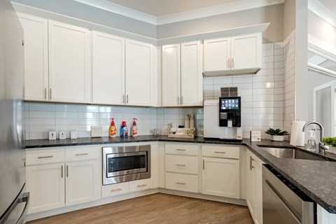 A kitchen with white cabinets and a black countertop.