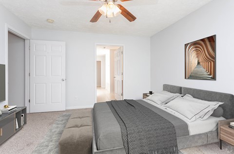 A bedroom with a large bed and a ceiling fan.