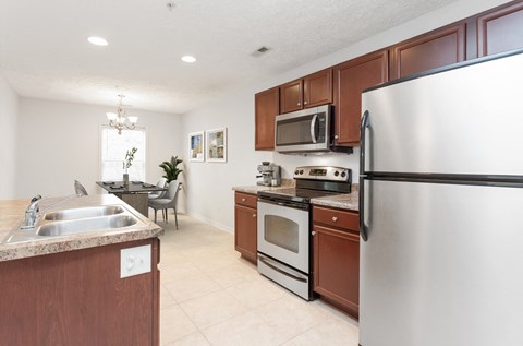 A kitchen with a stainless steel refrigerator, microwave, oven, and sink.