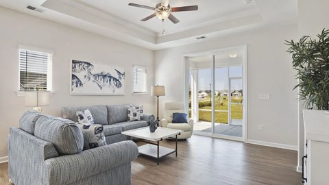 A living room with a grey couch and a painting on the wall.