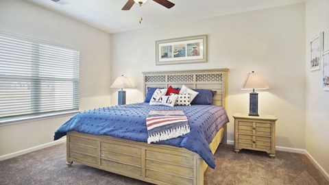 A bedroom with a bed, two lamps, and a ceiling fan.
